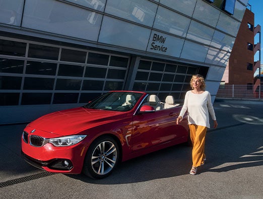 Customer walks past a parked BMW 4 Series outside a BMW Service Center.